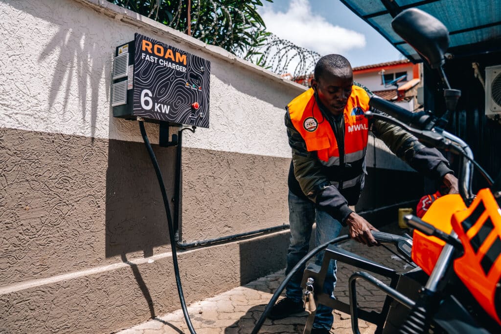 How might Charging as a Service work for electric motorcycle riders in East Africa? 1 Copy of 0.Boda boda Rider charging a Roam Air light electric vehicle at a Roam Point in Waiyaki Way